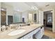 Bright bathroom with double sinks, vanity, tub, glass block window, and a door to the bedroom at 1727 Woodpond Way, Lutz, FL 33559