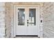 Home's double front doors framed by white-washed brick with glass windows and a modern video doorbell at 1727 Woodpond Way, Lutz, FL 33559