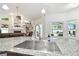 Stainless steel kitchen sink and granite countertops open to vaulted ceiling living room with fireplace at 1727 Woodpond Way, Lutz, FL 33559