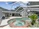 A luxurious backyard featuring a screened-in pool and hot tub, surrounded by comfortable lounge seating at 1727 Woodpond Way, Lutz, FL 33559