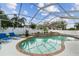 Screened-in pool with a brick waterfall feature, surrounded by ample patio space and lush landscaping at 1727 Woodpond Way, Lutz, FL 33559
