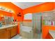 Bright bathroom with orange walls, separate tub and shower and a neutral vanity at 2539 Centennial Falcon Dr, Valrico, FL 33596