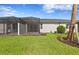 A spacious backyard features green grass, a screened-in patio, and a home with a gray exterior at 27148 Capri Shores Cir, Englewood, FL 34223