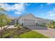 Charming home exterior with a paved driveway, two-car garage, and beautiful landscaping at 27148 Capri Shores Cir, Englewood, FL 34223