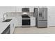 Modern kitchen features stainless steel appliances, white cabinets, and tile backsplash at 27148 Capri Shores Cir, Englewood, FL 34223