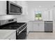 Beautiful kitchen features stainless steel appliances, white cabinets, countertops and sliding glass doors at 27152 Capri Shores Cir, Englewood, FL 34223