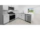Modern white kitchen featuring stainless steel appliances, white cabinets, countertops and a view into the living room at 27152 Capri Shores Cir, Englewood, FL 34223