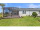 Landscaped backyard featuring a screened-in patio and lush lawn at 27156 Capri Shores Cir, Englewood, FL 34223