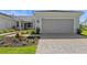 Charming home featuring a gray two-car garage, landscaped yard, and paver driveway at 27156 Capri Shores Cir, Englewood, FL 34223