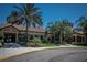 The Del Webb clubhouse features lush landscaping, benches, and an American flag at 305 Bluewater Falls Ct, Apollo Beach, FL 33572