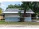 Side exterior view of light blue house, accented by lush greenery and a secure chain-link fence at 3409 N 10Th St, Tampa, FL 33605