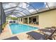 Relaxing screened-in pool area with stylish lounge chairs, a soothing hot tub, and an outdoor kitchen at 3503 Gaviota Dr, Sun City Center, FL 33573