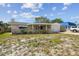 A one story home featuring a covered porch, attached garage, and mature landscaping at 3514 Truman Dr, Holiday, FL 34691