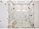 Luxurious walk-in shower with bench seating, marble-look tile, and modern fixtures at 4405 Barletta Ct, Wesley Chapel, FL 33543