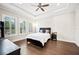 Bright bedroom featuring large windows with plantation shutters, tray ceiling, and hardwood floors at 4405 Barletta Ct, Wesley Chapel, FL 33543