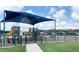 Community playground with sun shade, slide, climbing area and benches for parents to relax at 5154 Brickwood Rise Dr, Wimauma, FL 33598