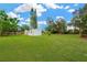 Expansive backyard featuring a well-manicured lawn, mature trees, storage sheds, and a charming fence at 602 Stephens Rd, Ruskin, FL 33570