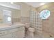 Bathroom area featuring toilet, sink with vanity, and glass-blocked shower stall with stained glass window at 6056 Fall River Dr, New Port Richey, FL 34655