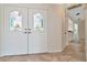 Elegant foyer featuring tile flooring and decorative glass double doors with a partial view of kitchen at 6056 Fall River Dr, New Port Richey, FL 34655