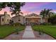 Charming home at dusk showcasing manicured lawn, inviting entrance, and warm exterior lighting at 636 16Th Ne Ave, St Petersburg, FL 33704