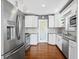 Galley kitchen with stainless steel appliances, white cabinets, gray walls and hardwood floors at 636 16Th Ne Ave, St Petersburg, FL 33704