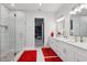 Bright bathroom featuring a double sink vanity, glass enclosed shower, and marble tiling at 714 S Lois Ave, Tampa, FL 33609