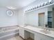 Bathroom features a double sink vanity, tub, decorative window, and tile flooring at 9308 Fairway Lakes Ct, Tampa, FL 33647