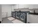Well-lit laundry room with three front-load washing machines and dryers and modern white cabinetry at 98 W Davis Blvd, Tampa, FL 33606