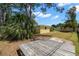 Backyard view with a small yellow outbuilding and a small concrete area that can serve as a patio at 1019 Goshen Rd, Tarpon Springs, FL 34689