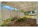 View of an outdoor covered patio area with lattice and lots of surrounding natural vegetation at 1019 Goshen Rd, Tarpon Springs, FL 34689