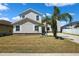Charming two-story home with stone accents, lush lawn, and mature palm trees against a clear blue sky at 11907 Streambed Dr, Riverview, FL 33579