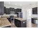 Modern kitchen features dark cabinets, granite countertops, stainless steel appliances, and a kitchen island at 11907 Streambed Dr, Riverview, FL 33579
