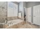 Bright bathroom with a soaking tub, shuttered window, and gray-toned tile flooring at 12523 Riverglen Dr, Riverview, FL 33569