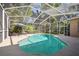 Serene screened-in pool with a lush, green backdrop, complemented by an umbrella and lounge chairs at 12523 Riverglen Dr, Riverview, FL 33569