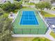 Aerial view of a well-maintained, fenced tennis court with green and blue surface and a parking area nearby at 130 Sabal Ct # C, Oldsmar, FL 34677