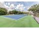 Well-maintained blue and green tennis court with a dark fence, nestled in a green community at 130 Sabal Ct # C, Oldsmar, FL 34677