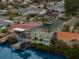 An aerial view shows the home's dock, pool, patio, and lush landscaping situated on the water at 139 Wall St, Redington Shores, FL 33708