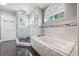 Bright bathroom features marble tile, a glass shower, a soaking tub, and an arched window at 139 Wall St, Redington Shores, FL 33708