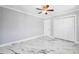 Bedroom with white marble floors, a modern ceiling fan, and a closet, complemented by neutral-toned walls at 139 Wall St, Redington Shores, FL 33708