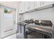 Laundry room with modern washer and dryer and white cabinets at 139 Wall St, Redington Shores, FL 33708