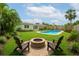 Landscaped backyard featuring a pool, fire pit, lush lawn, and tropical plants at 1758 Southview Rd, Largo, FL 33770