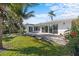 A backyard of a house with a patio and surrounded by palms and green grass at 2540 S Shore Se Dr, St Petersburg, FL 33705
