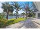 Landscaped backyard with paver patio, lush lawn, palm trees, and canal view with dock at 2540 S Shore Se Dr, St Petersburg, FL 33705