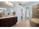 Bright bathroom featuring a dual sink vanity, soaking tub, and glass-enclosed shower at 3009 Sheehan Dr, Land O Lakes, FL 34638