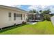 View of the home's exterior featuring a screened patio and well-manicured lawn and landscaping at 3009 Sheehan Dr, Land O Lakes, FL 34638