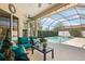 Comfortable screened patio seating area with blue cushions overlooking the pool and lush landscaping at 3009 Sheehan Dr, Land O Lakes, FL 34638