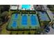 Aerial view showcasing tennis courts with blue surfaces, surrounded by lush greenery and palm trees, providing a scenic sports environment at 3009 Sheehan Dr, Land O Lakes, FL 34638