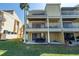 Rear view of a three-story condo building with multiple balconies and a patio area at 472 Sandy Hook Rd, Treasure Island, FL 33706