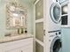 Bathroom featuring a granite countertop vanity, decorative mirror, and stacked washer-dryer at 5200 Brittany S Dr # 1502, St Petersburg, FL 33715