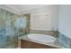 A luxurious bathroom featuring marble tiling, a soaking tub, and a glass-enclosed shower at 597 Bay St, Palm Harbor, FL 34683